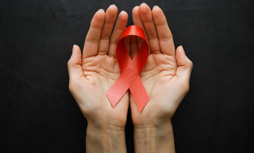 Unas manos sostienen un listón rojo, símbolo de la lucha contra el VIH.