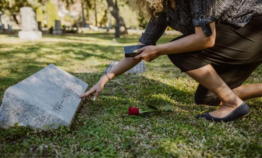 Una mujer toca la lápida de un ser querido en un recinto funerario.