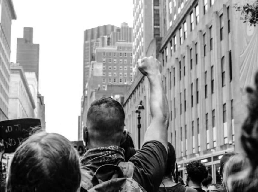 Hombre levanta su puño durante una manifestación pública en la calle.