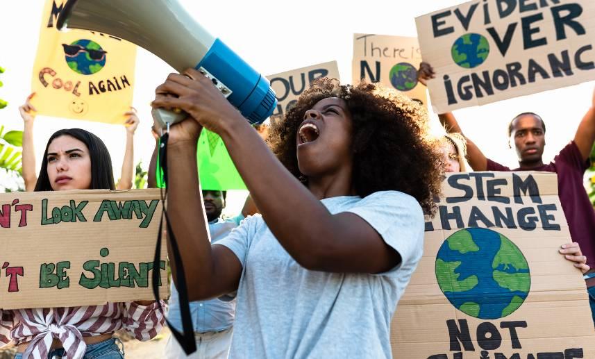 Mujer sostiene un megáfono mientras con otro grupo de personas tienen una manifestación pacífica a favor del medio ambiente.