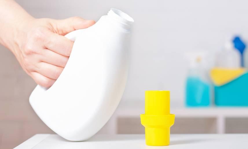 Botella de plástico normalmente usada para detergente de ropa en una mesa.