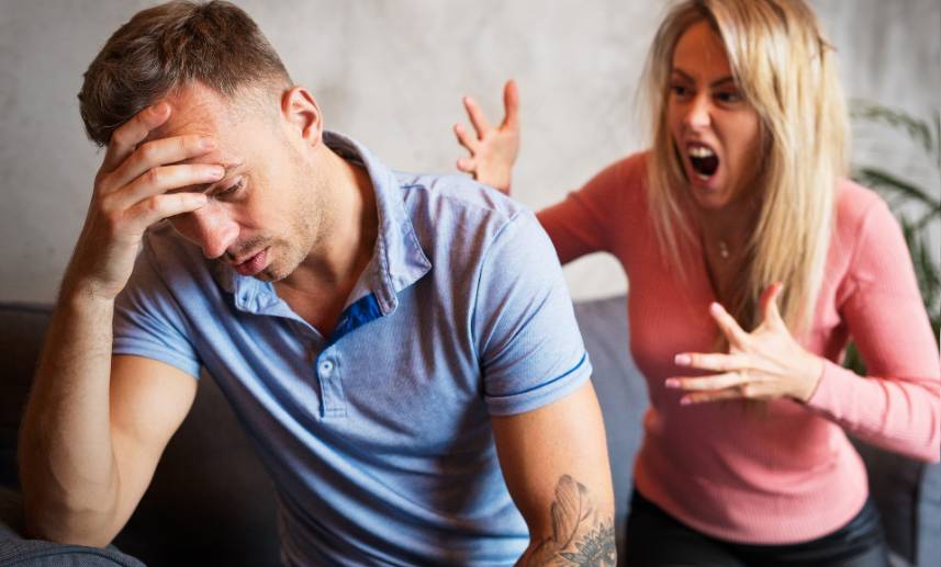 Hombre con mirada hacia abajo toca su cabeza mientras una mujer le grita desesperadamente.
