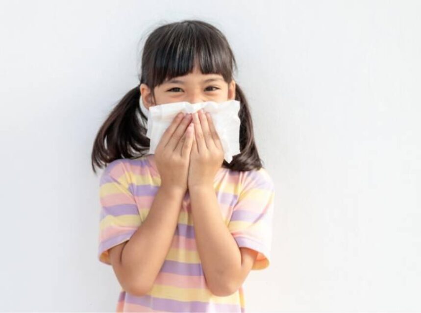 Una niña sostiene con sus manos una toalla con la que cubre su boca y nariz.