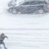 Ola de frío en Estados Unidos. Persona camina por una calle en el medio de una tormenta de nieve.