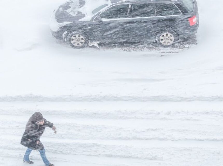 Ola de frío en Estados Unidos. Persona camina por una calle en el medio de una tormenta de nieve.