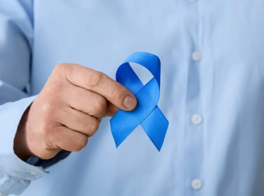 Mano de hombre sostiene un listón azul en señal de apoyo a la lucha contra el cáncer de colón.