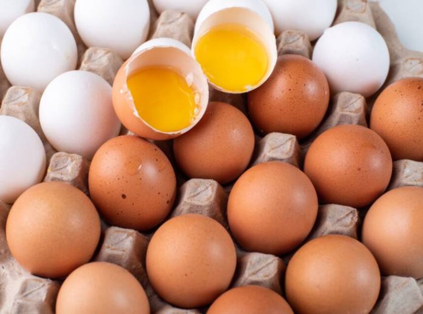 Carpeta de huevos, contiene huevos de gallina blancos y café. Dos huevos están abiertos y se ve la yema.