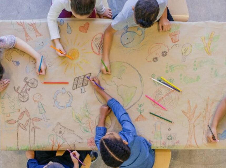 Grupo de infantes en una mesa dibujando sobre temas ambientales.