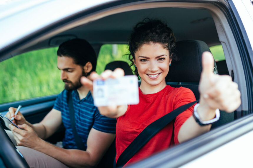 Muchacha muestra orgullosa su licencia de conducir dentro de un vehículo. Aprende cómo sacar una licencia de conducir en estados unidos sin papeles.
