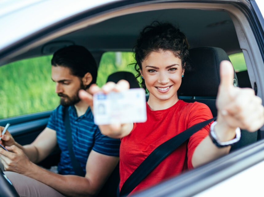 Muchacha muestra orgullosa su licencia de conducir dentro de un vehículo. Aprende cómo sacar una licencia de conducir en estados unidos sin papeles.