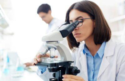 Una científica está analizando unas pruebas con un microscopio.