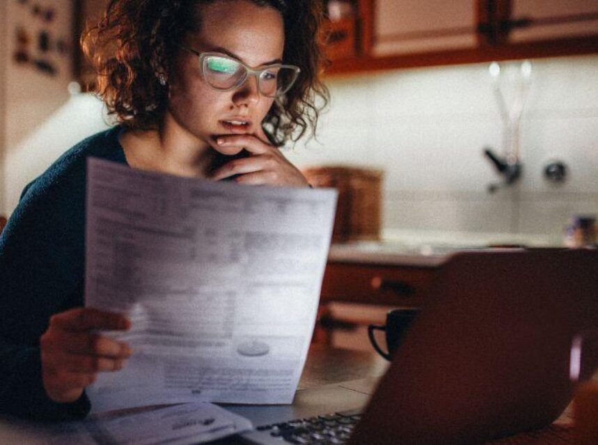Mujer mira pantalla de computadora preocupada. Aprende cuáles son las consecuencias de declararse en bancarrota en Estados Unidos.