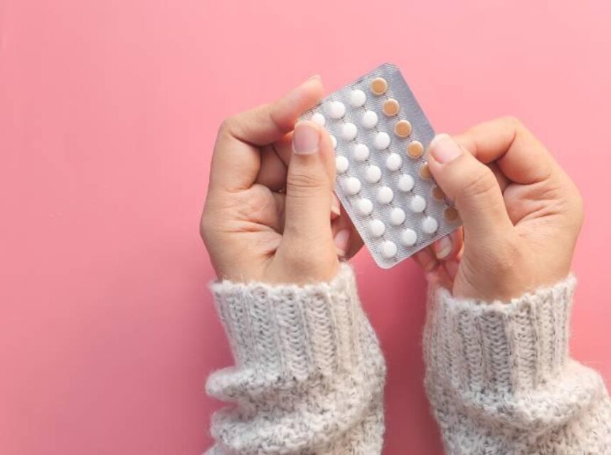 Manos sostienen pastillas anticonceptivas sobre un fondo rosa. ¿Puedo comprar pastillas anticonceptivas sin receta en Estados Unidos? Te contamos lo que debes saber sobre las pastillas anticonceptivas en Estados Unidos.