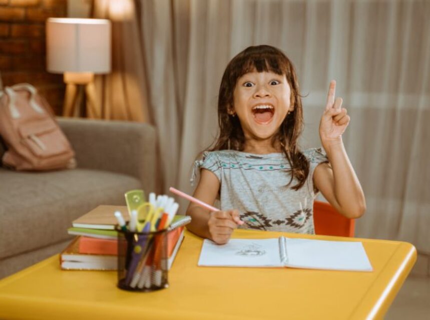 Una niña emocionada tiene una idea mientras está haciendo una tarea escolar.