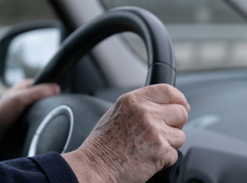 Manos de una persona adulta mayor sobre el volante de un automóvil.