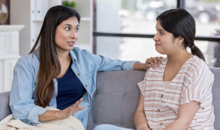Dos jóvenes mujeres conversan en un sofa. Una de ellas parece que está estableciendo límites.