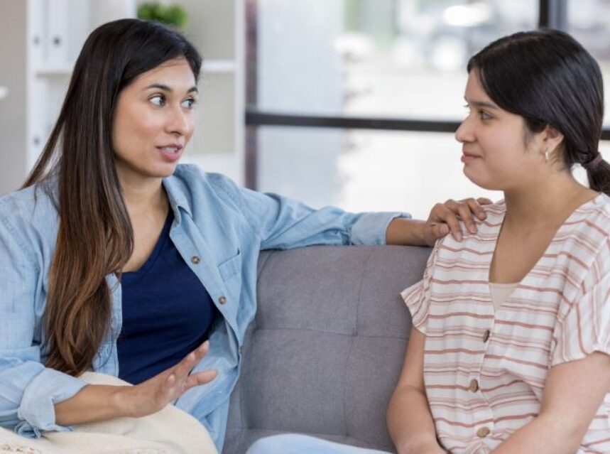 Dos jóvenes mujeres conversan en un sofa. Una de ellas parece que está estableciendo límites.