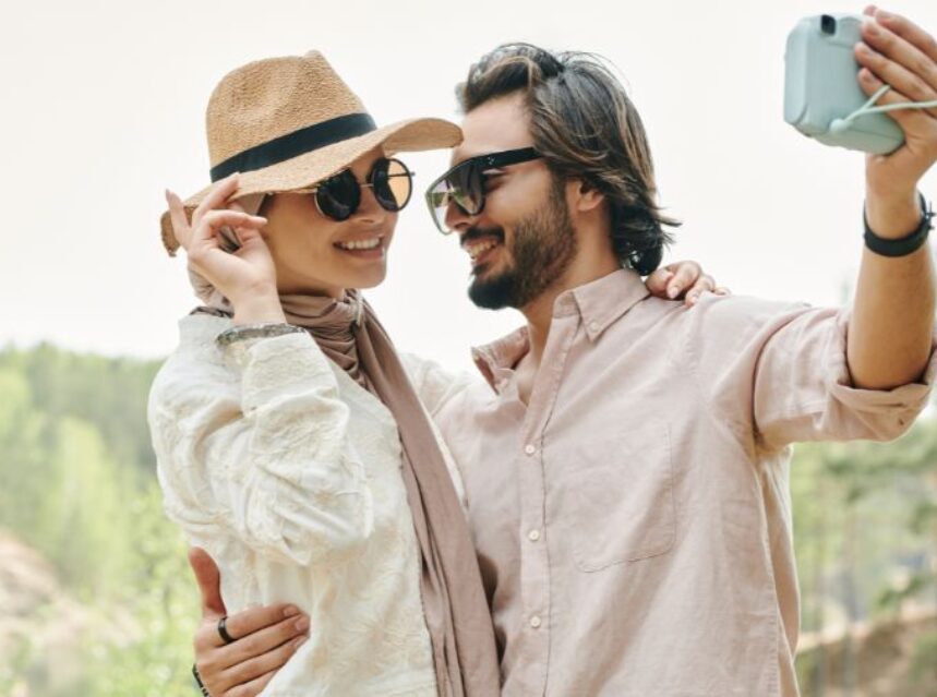 Una pareja sonríe mientras se toman una selfie en un entorno natural.