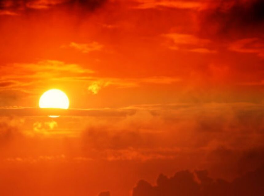 Un sol brillante entre nubes rojas.