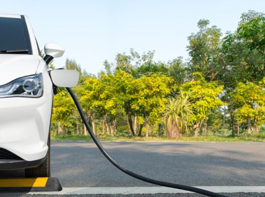 Vehículo eléctrico siendo cargado de energía con un fondo de un verde bosque.