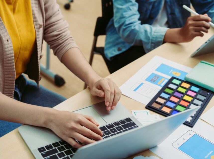 Dos personas en un escritorio con tablet y laptop, trabajando en algo.