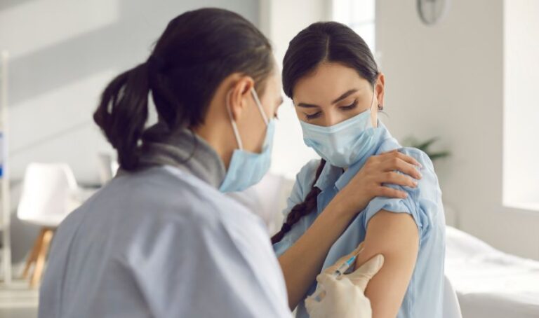 Mujer recibe vacuna por personal médico.