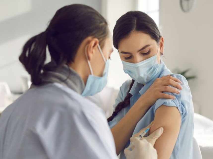 Mujer recibe vacuna por personal médico.