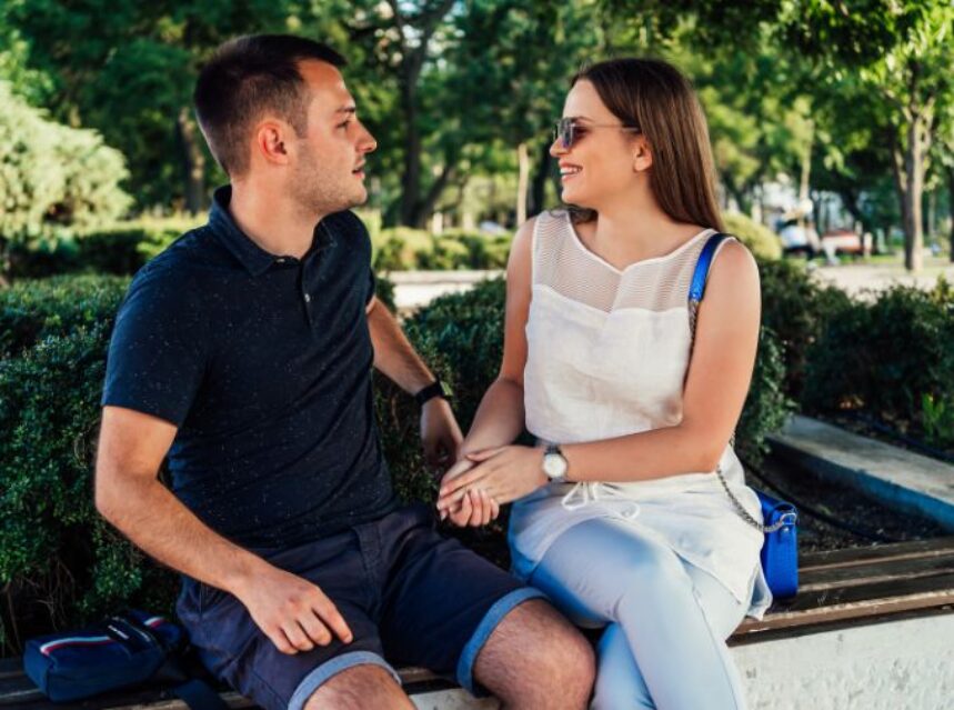 Una pareja sentada en una banca de un parque sostiene una armoniosa conversación.