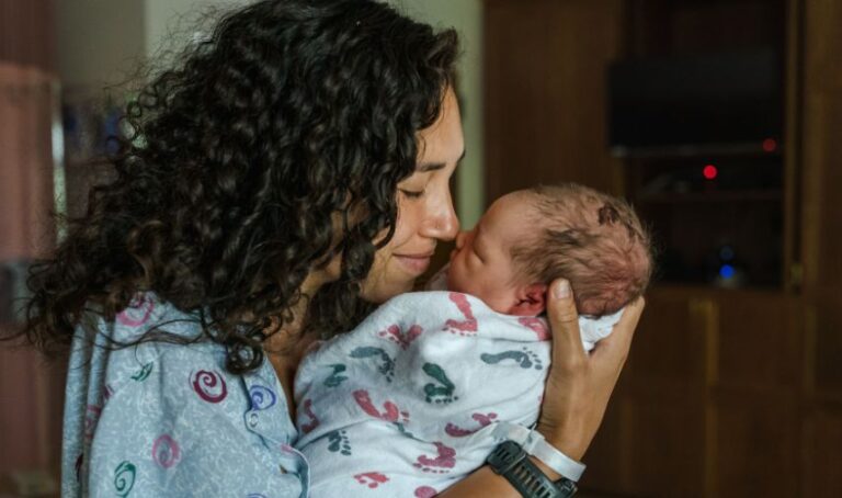 Una madre de un recién nacido une su nariz con la del bebé.