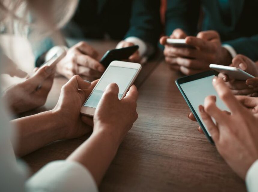 Manos de 4 personas sosteniendo sus teléfonos celulares.