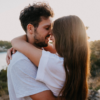 Una pareja se abraza tiernamente con un paisaje natural al fondo.