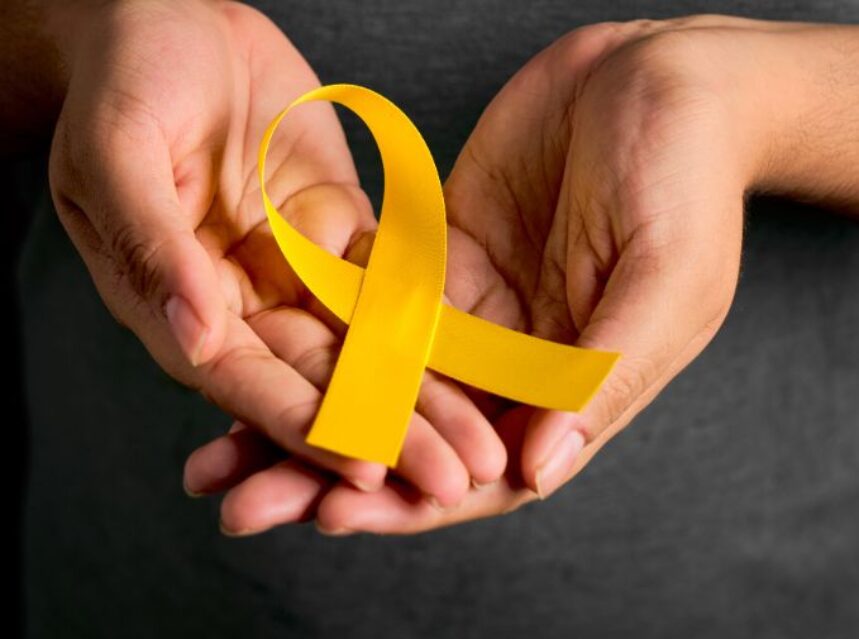 Un par de manos sostienen un listón amarillo, símbolo de la prevención del suicidio.