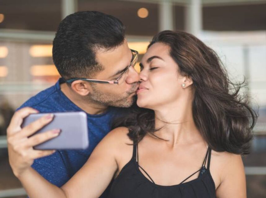 a man kissing a woman selfie