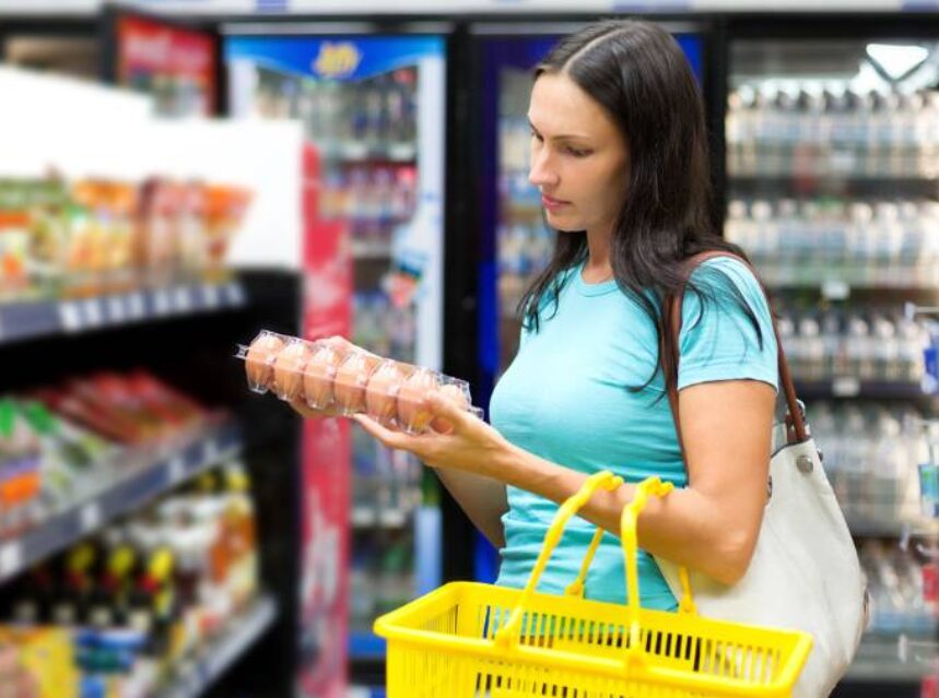 a woman holding a cart of eggs in a supermarket