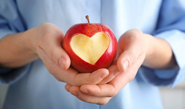 a person holding an apple with a heart cut out