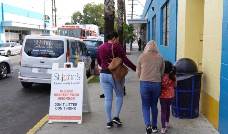 Familia latina camina por la acera.